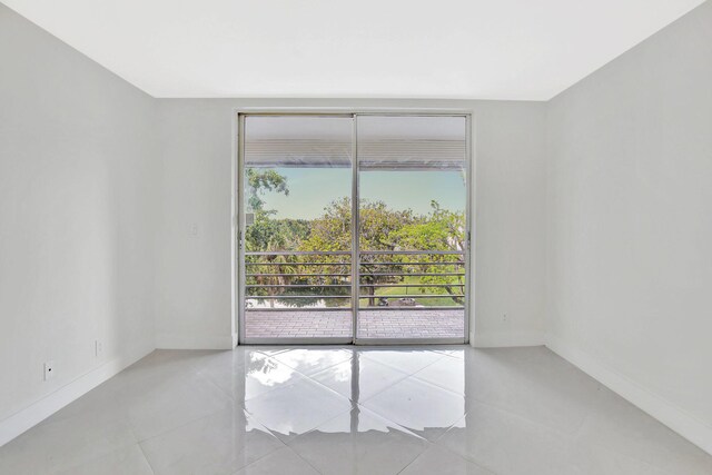spare room featuring tile patterned flooring, baseboards, and a wealth of natural light