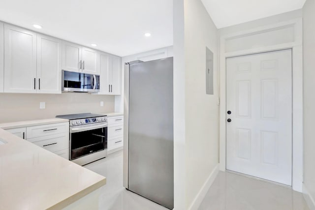kitchen with white cabinets, light countertops, stainless steel appliances, baseboards, and electric panel