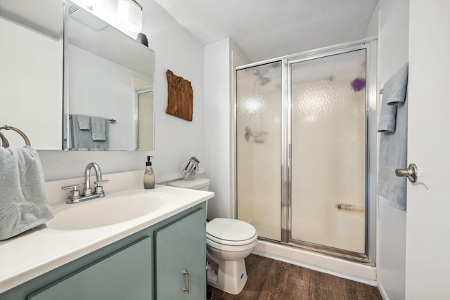 bathroom with hardwood / wood-style flooring, vanity, toilet, and a shower with shower door