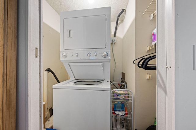 clothes washing area featuring stacked washer and clothes dryer and a textured ceiling