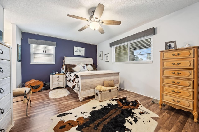 bedroom featuring ceiling fan, dark hardwood / wood-style flooring, and a textured ceiling