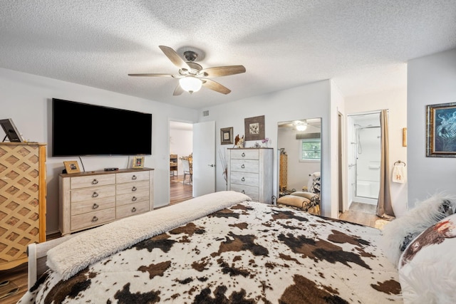 bedroom featuring ceiling fan, ensuite bathroom, hardwood / wood-style floors, and a textured ceiling