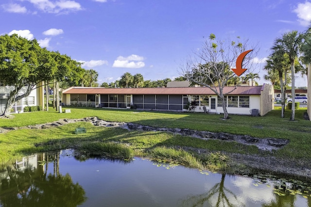 rear view of property featuring a lawn and a water view