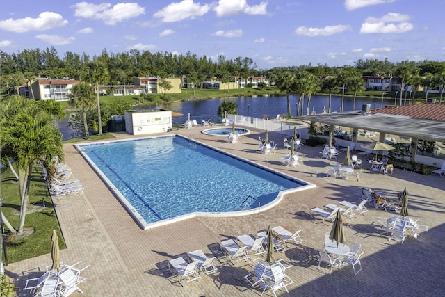 view of swimming pool with a water view, a hot tub, and a patio area