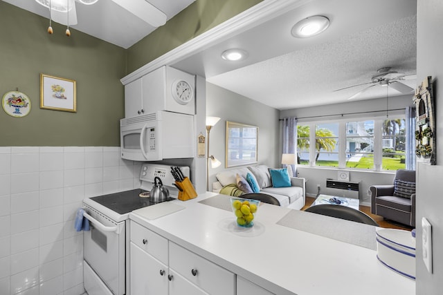 kitchen with white cabinetry, a textured ceiling, ceiling fan, and white appliances