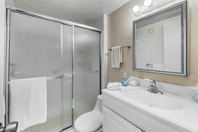 bathroom with tile walls, vanity, toilet, and walk in shower