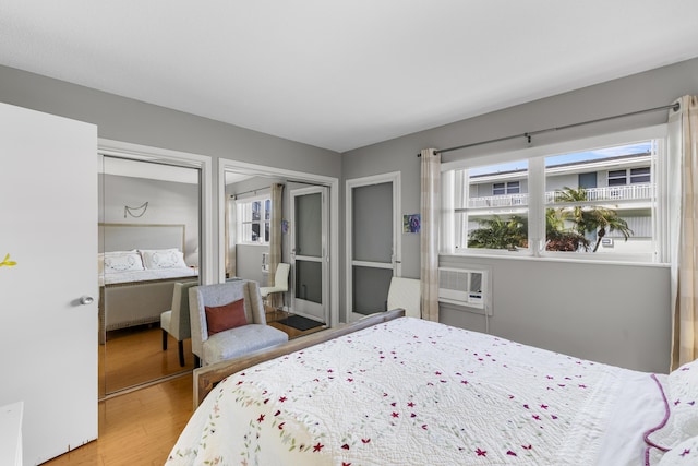 bedroom with multiple closets, hardwood / wood-style flooring, and a wall mounted AC