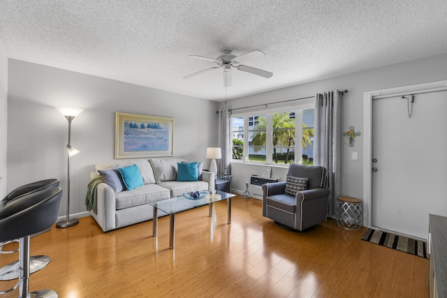 living room with ceiling fan, hardwood / wood-style floors, and a textured ceiling