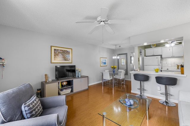 living room featuring hardwood / wood-style flooring, ceiling fan, and a textured ceiling