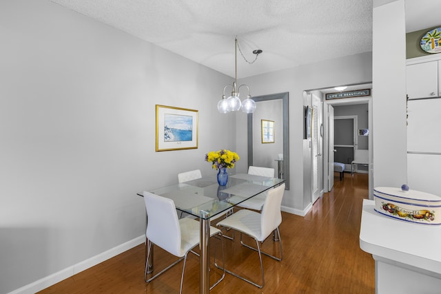 dining space featuring wood-type flooring and a textured ceiling