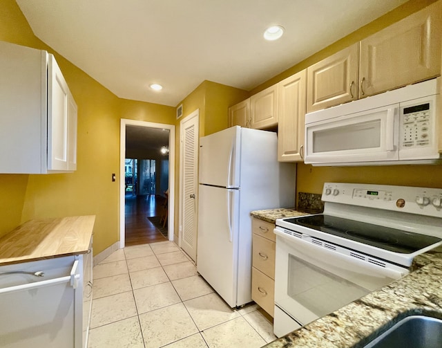 kitchen featuring light stone counters, white appliances, and light tile patterned floors