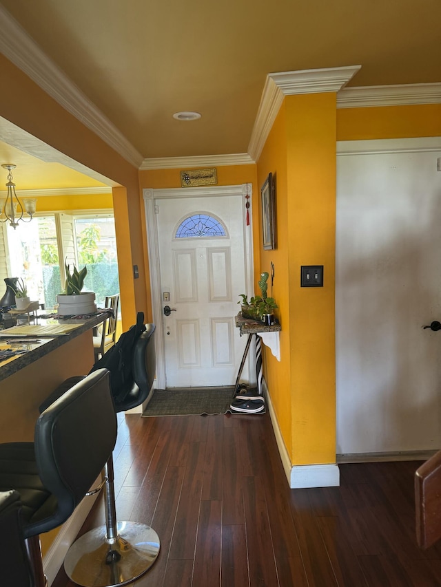 foyer with dark hardwood / wood-style flooring, crown molding, and an inviting chandelier