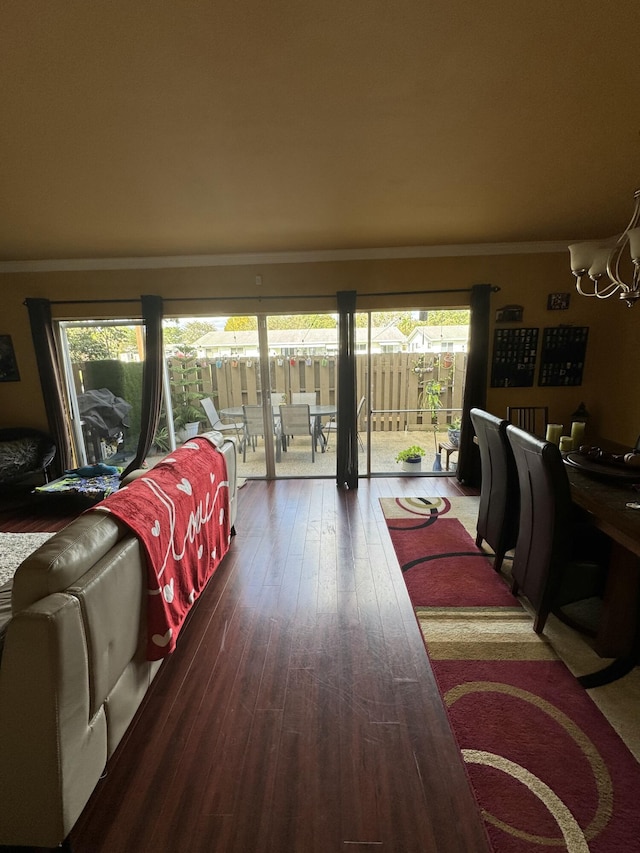 living room with hardwood / wood-style flooring, ornamental molding, and a notable chandelier