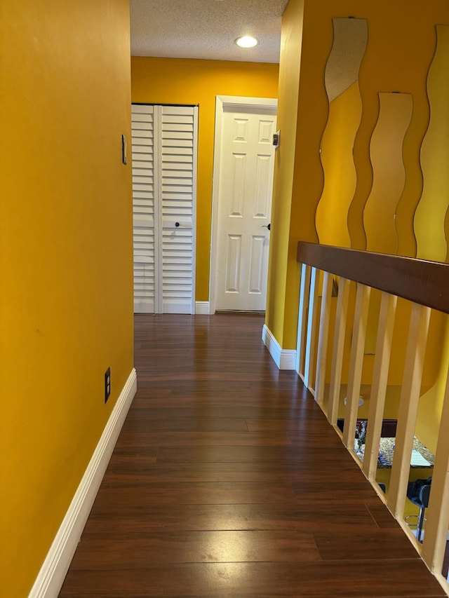 hallway featuring dark wood-type flooring and a textured ceiling