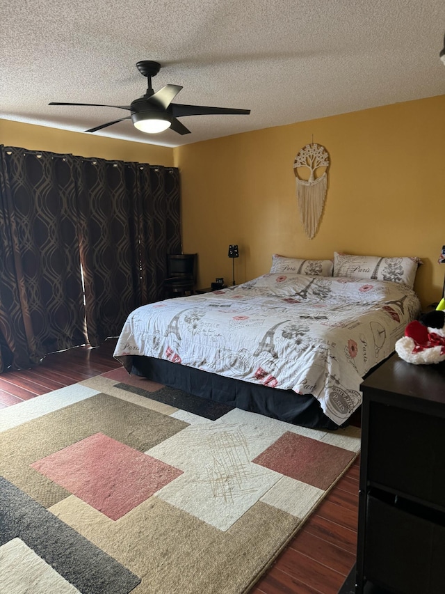 bedroom with ceiling fan, dark hardwood / wood-style flooring, and a textured ceiling