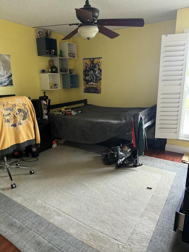 bedroom with dark hardwood / wood-style flooring, ceiling fan, and a textured ceiling