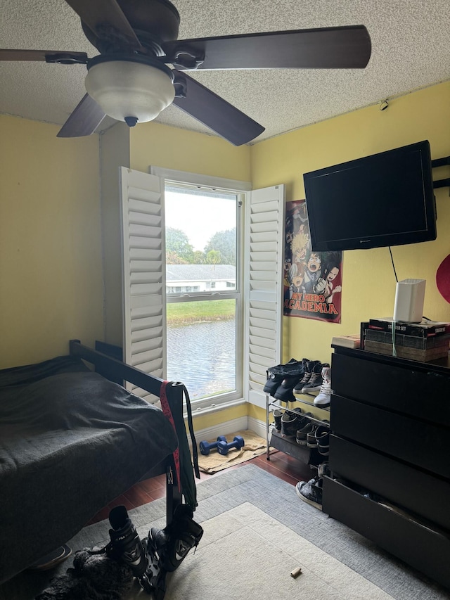 bedroom featuring ceiling fan, light hardwood / wood-style floors, and a textured ceiling