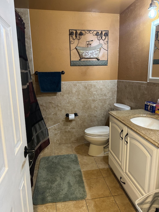 bathroom featuring tile walls, vanity, tile patterned floors, and toilet