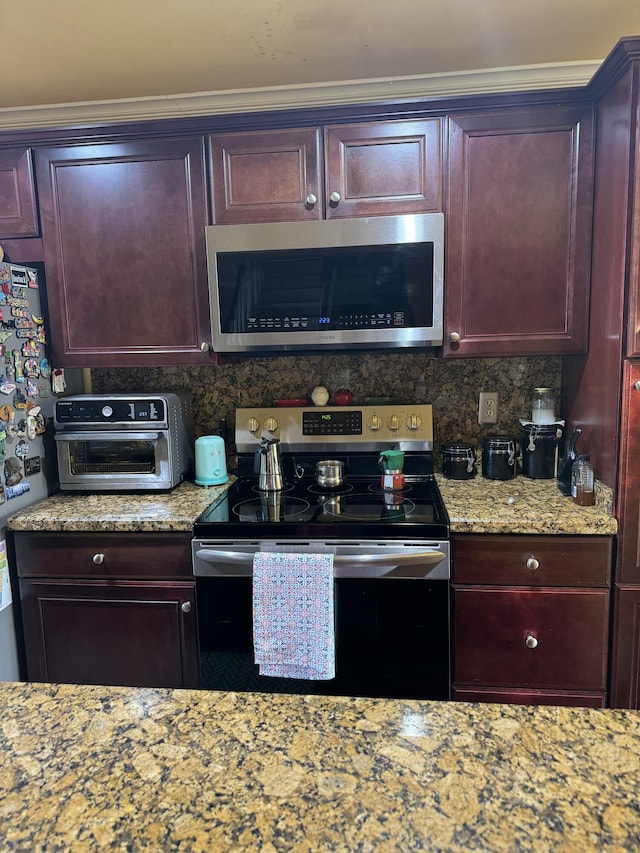 kitchen with light stone counters, appliances with stainless steel finishes, and backsplash