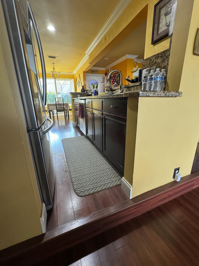 kitchen featuring stone countertops, ornamental molding, appliances with stainless steel finishes, dark hardwood / wood-style flooring, and kitchen peninsula