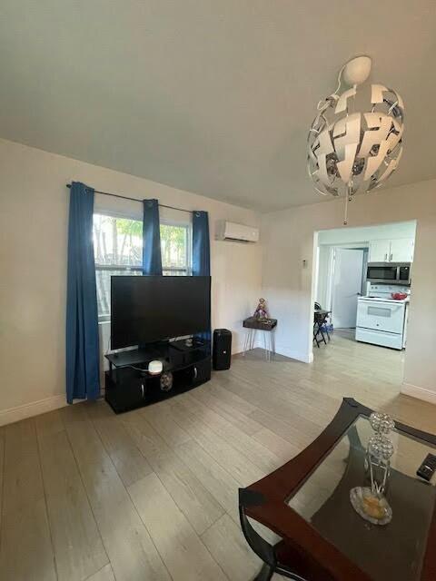 living room with an AC wall unit and light wood-type flooring