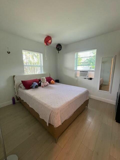 bedroom featuring cooling unit, multiple windows, and light wood-type flooring