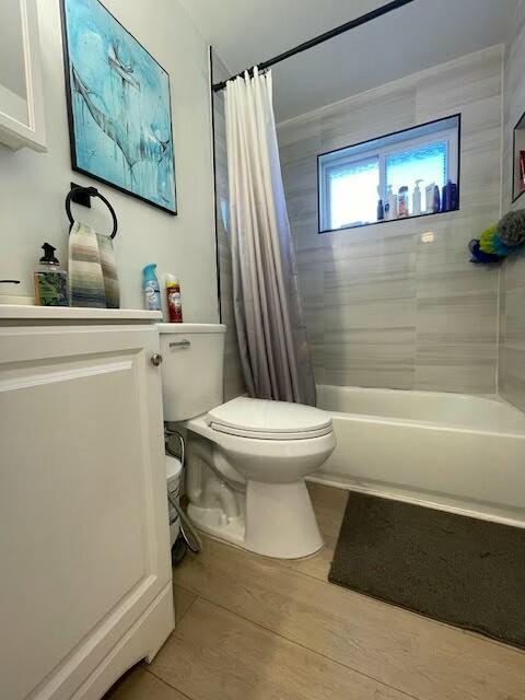 full bathroom featuring vanity, wood-type flooring, shower / tub combo, and toilet