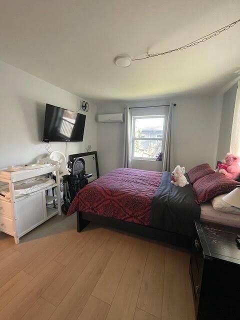 bedroom featuring wood-type flooring and a wall unit AC