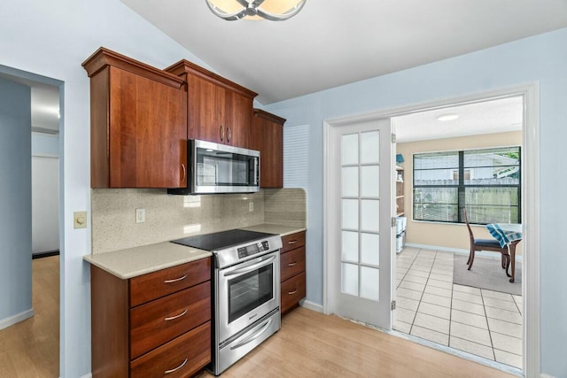 kitchen featuring appliances with stainless steel finishes, light wood-type flooring, and decorative backsplash