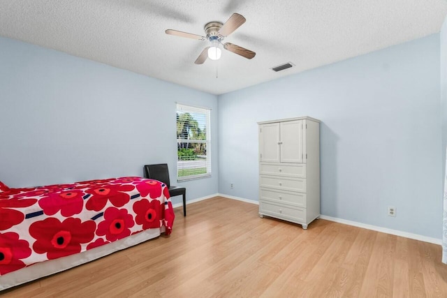 bedroom featuring ceiling fan, a textured ceiling, and light hardwood / wood-style floors