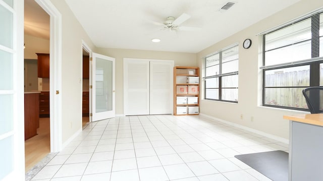 interior space featuring light tile patterned floors, ceiling fan, and a closet