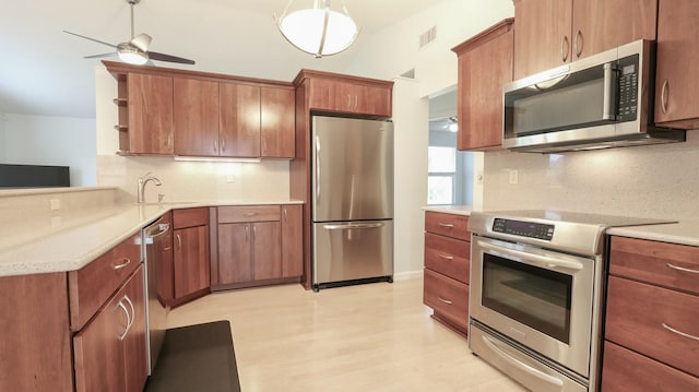 kitchen featuring sink, ceiling fan, hanging light fixtures, stainless steel appliances, and tasteful backsplash