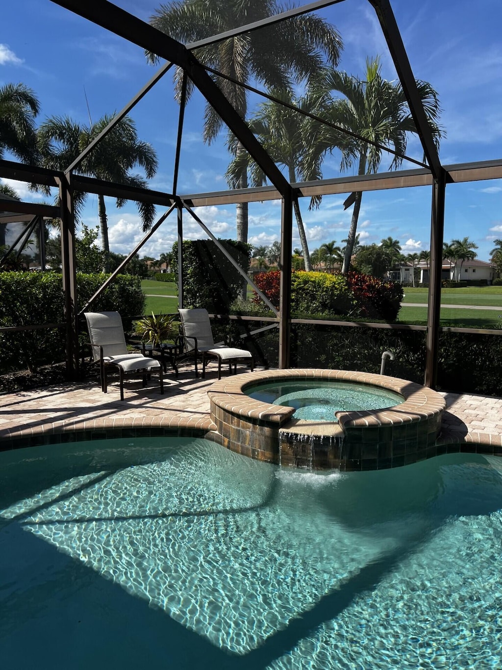 view of pool with an in ground hot tub, a patio area, and glass enclosure