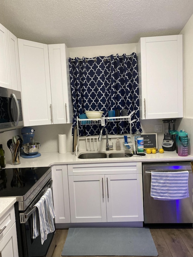 kitchen with white cabinets, appliances with stainless steel finishes, sink, and dark wood-type flooring