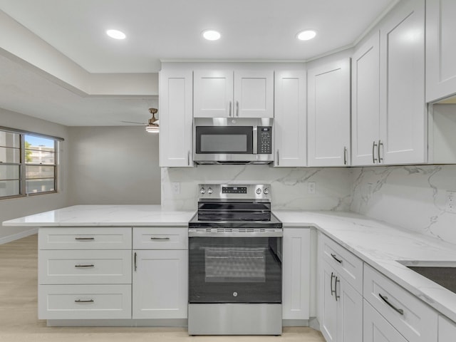 2030 Hythe B 2030, Boca Raton, FL 33434 - kitchen with tasteful backsplash, light stone counters, appliances with stainless steel finishes, kitchen peninsula, and white cabinets
