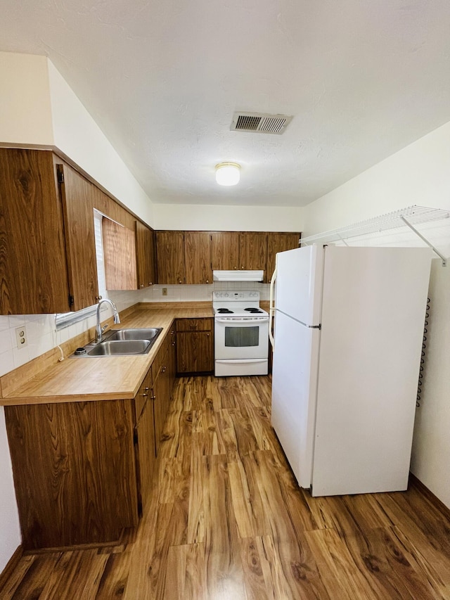 kitchen featuring sink, white appliances, light hardwood / wood-style flooring, and decorative backsplash