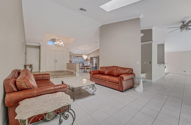 living room with ornamental molding, vaulted ceiling with skylight, light tile patterned flooring, and ceiling fan with notable chandelier