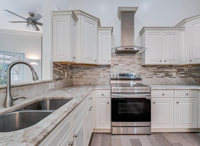 kitchen with stainless steel range with electric stovetop, sink, tasteful backsplash, and wall chimney range hood