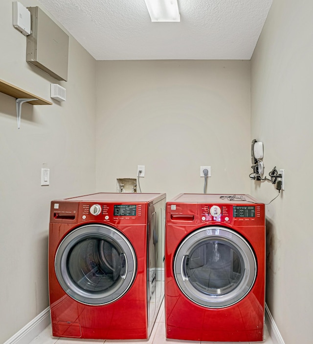 clothes washing area with washer and dryer and a textured ceiling