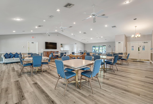 dining area featuring ceiling fan with notable chandelier, lofted ceiling, and light hardwood / wood-style flooring