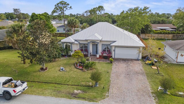 view of front of property featuring a garage, a front yard, decorative driveway, and metal roof