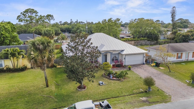 view of front facade featuring a garage, metal roof, fence, decorative driveway, and a front lawn