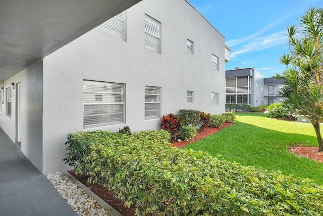 view of side of property featuring a lawn and stucco siding