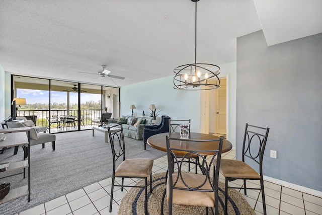 tiled dining space featuring ceiling fan with notable chandelier, expansive windows, and a textured ceiling