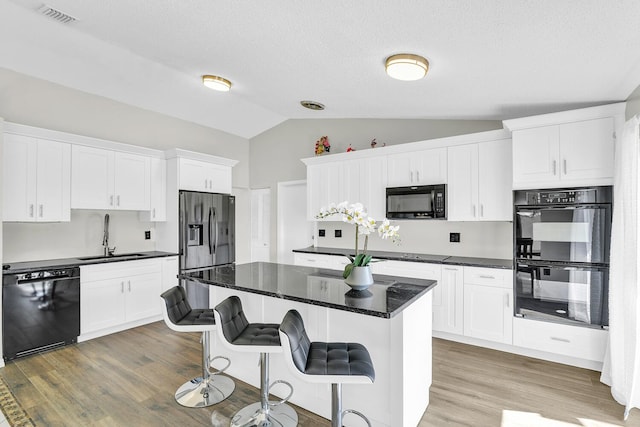 6335 Hitchin Post Way, Delray Beach, FL 33484 - kitchen featuring black appliances, lofted ceiling, light wood-type flooring, and white cabinets