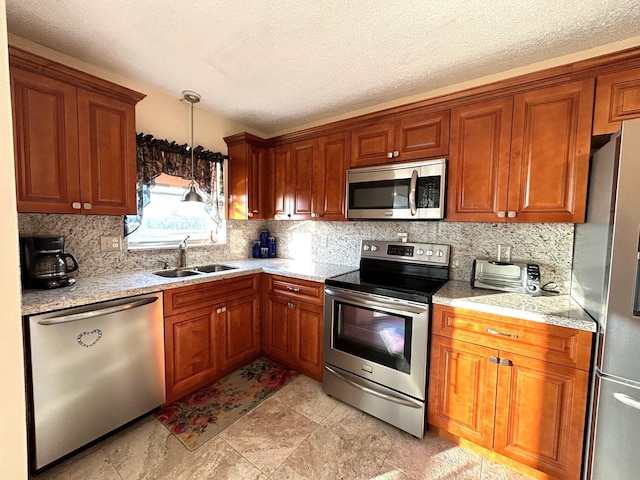 kitchen with hanging light fixtures, light stone countertops, appliances with stainless steel finishes, and sink