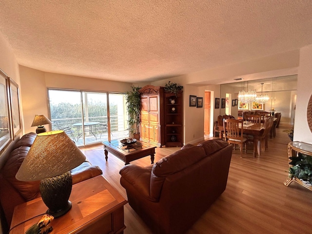 living room featuring a notable chandelier, hardwood / wood-style flooring, and a textured ceiling