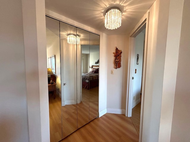 hallway featuring hardwood / wood-style flooring and a chandelier