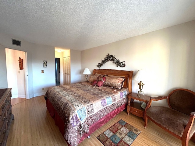 bedroom with a textured ceiling, light wood-type flooring, and a closet