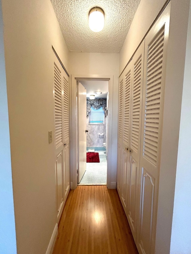 hall featuring light hardwood / wood-style flooring and a textured ceiling